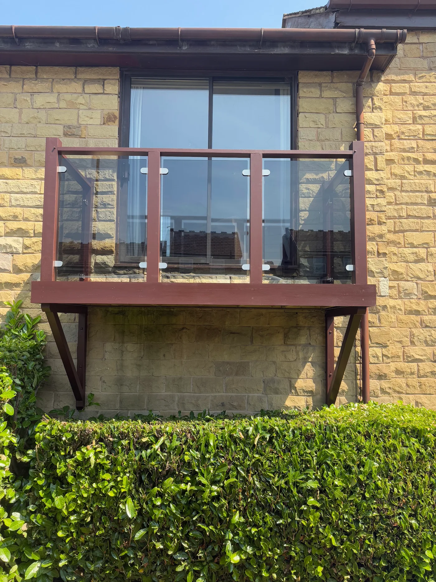 An exterior balcony with timber supports and glass panels